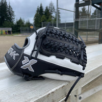 Black and white softball glove on a wooden bench with a sports field background