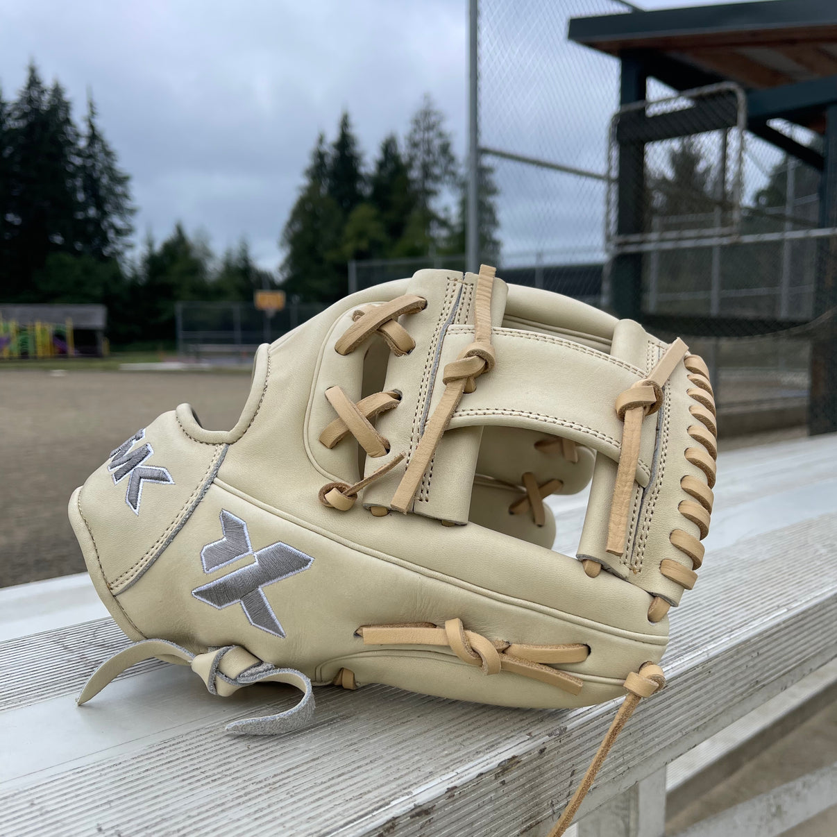 Baseball glove on a wooden bench with a baseball field background