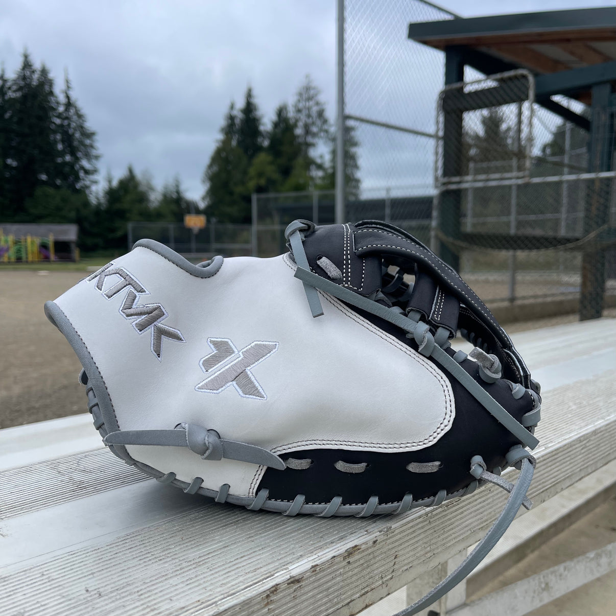 Softball mitt on a wooden bench with a sports field background