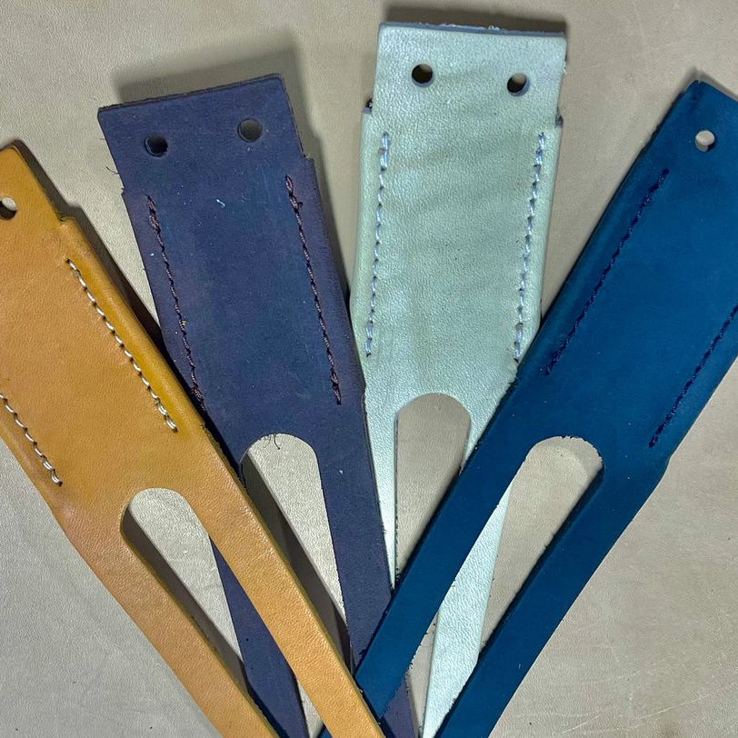 Five leather straps in different colors on a beige surface