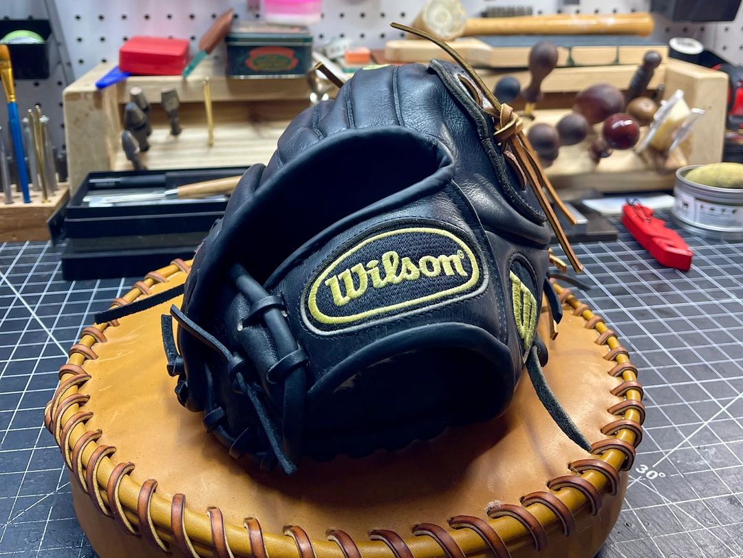 Black Wilson baseball glove on a wooden stand with a workshop background